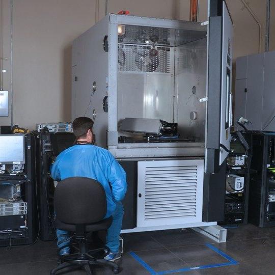 Man dressed in protective blue suit sitting in a chair performing antenna testing services